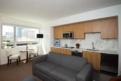 a living room with a couch and a kitchen at The Study at University City, Study Hotels in Philadelphia