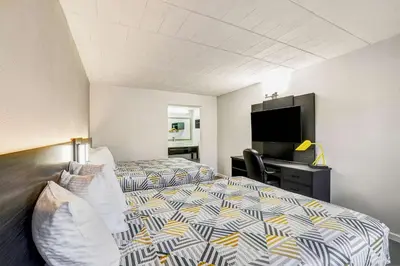 a hotel room with two beds and a flat screen tv at Motel 6 Carlisle, PA - Cumberland Valley in Carlisle