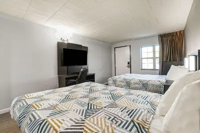a hotel room with two beds and a flat screen tv at Motel 6 Carlisle, PA - Cumberland Valley in Carlisle