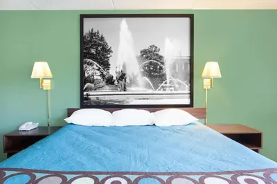 a bedroom with a blue bed with a picture of a fountain at Super 8 by Wyndham Harrisburg Hershey West in Harrisburg