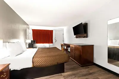 a hotel room with a bed and a flat screen tv at Rodeway Inn Brooklawn in Brooklawn