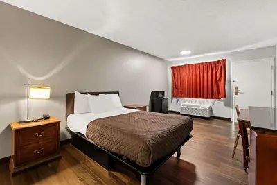 a hotel room with a bed and a red curtain at Rodeway Inn Brooklawn in Brooklawn