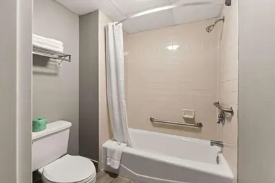 a bathroom with a toilet and a tub and a sink at Rodeway Inn Brooklawn in Brooklawn