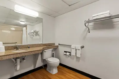 a bathroom with a toilet and a sink and a mirror at Rodeway Inn Brooklawn in Brooklawn