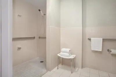 a bathroom with a shower and a stool with towels at Days Inn by Wyndham Reading Wyomissing in Reading