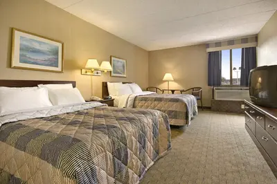 a hotel room with two beds and a flat screen tv at Days Inn by Wyndham Reading Wyomissing in Reading