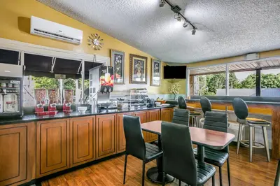 a kitchen with a bar with chairs and a table at Scottish Inns Harrisburg-Hershey South in New Cumberland