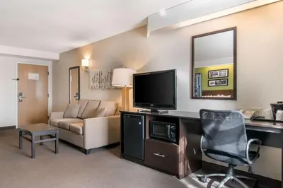 a room with a desk with a television and a couch at Sleep Inn Carlisle South in Carlisle