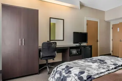 a bedroom with a bed and a desk with a television at Sleep Inn Carlisle South in Carlisle