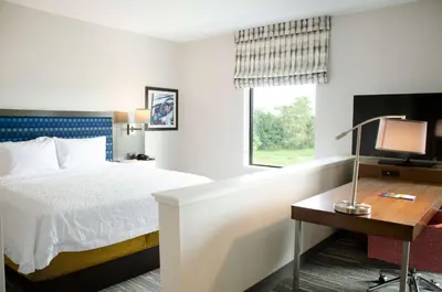 a hotel room with a bed and a desk with a television at Hampton Inn Lebanon in Lebanon
