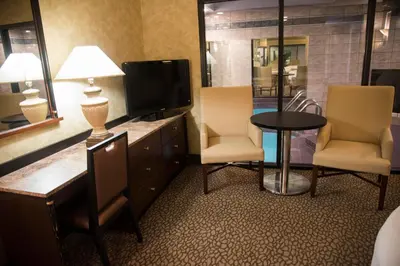 a hotel room with a tv and two chairs and a table at Paradise Stream Resort in Cresco