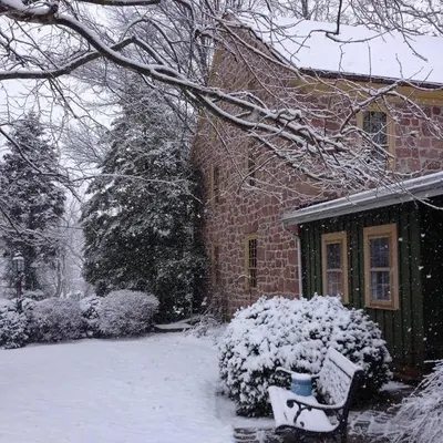 a bench covered in snow in front of a house at Brownstone Colonial Inn in Reinholds