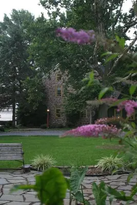 a stone house with a bench in a yard at Brownstone Colonial Inn in Reinholds