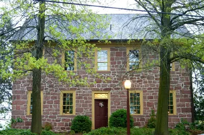 a brick house with a red door and trees at Brownstone Colonial Inn in Reinholds