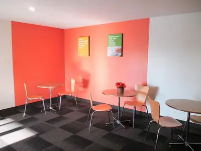 a waiting room with tables and chairs and orange walls at Motel 6-Drums in Drums