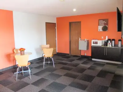 a kitchen with orange walls and a table and chairs at Motel 6-Drums in Drums