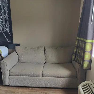 a couch sitting in a living room next to a window at Super 8 by Wyndham Allentown Kutztown Area in Kutztown