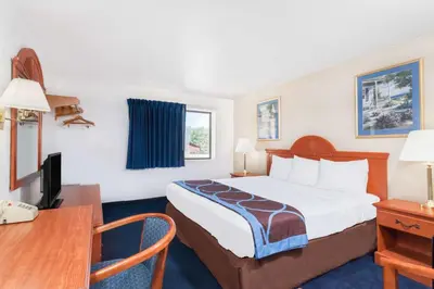 a small hotel room with a bed and a desk at Super 8 by Wyndham Montgomery Maybrook in Montgomery