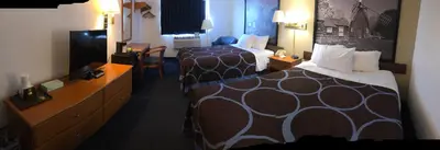 a hotel room with two beds and a flat screen tv at Super 8 by Wyndham Montgomery Maybrook in Montgomery