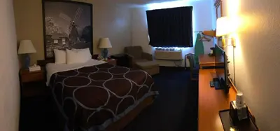 a hotel room with a large bed and a chair at Super 8 by Wyndham Montgomery Maybrook in Montgomery