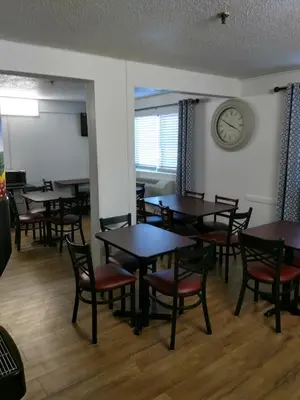 a dining room with tables and chairs and a clock at Super 8 by Wyndham Montgomery Maybrook in Montgomery