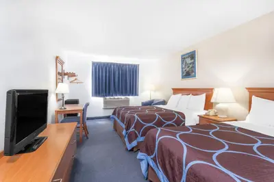 a hotel room with two beds and a flat screen tv at Super 8 by Wyndham Montgomery Maybrook in Montgomery