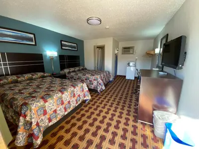 a hotel room with two beds and a flat screen tv at Lodge Inn Wrightstown - Fort Dix in Wrightstown