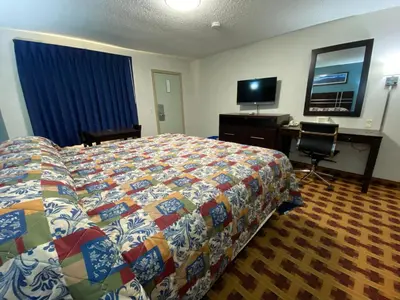 a hotel room with a bed and a desk and a television at Lodge Inn Wrightstown - Fort Dix in Wrightstown