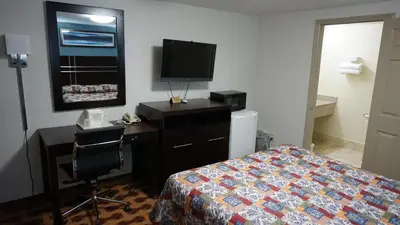 a bedroom with a bed and a desk and a television at Lodge Inn Wrightstown - Fort Dix in Wrightstown