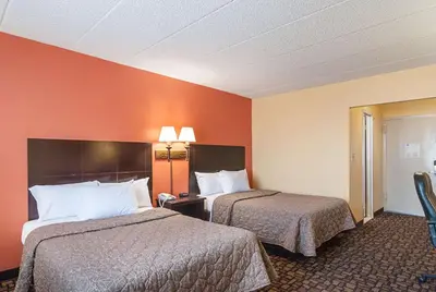 two beds in a hotel room with orange walls at Rodeway Inn Meadowlands in Secaucus