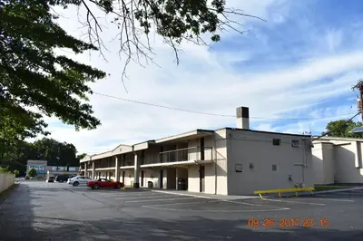 a large white building with a parking lot at MHO Hotel Bordentown in Bordentown