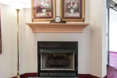 a fireplace with a clock and two pictures on the wall at Econo Lodge Carlisle in Carlisle