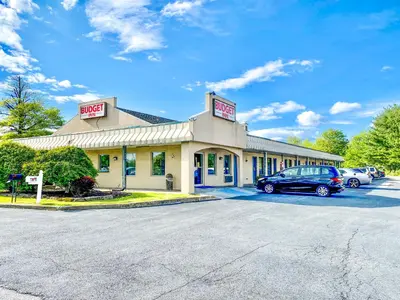 a building with a car parked in a parking lot at Budget Inn New Cumberland-Harrisburg-Hershey-York in New Cumberland
