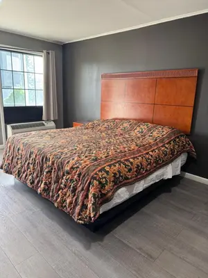 a bedroom with a large bed with a wooden headboard at Budget Inn New Cumberland-Harrisburg-Hershey-York in New Cumberland