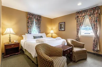 a hotel room with a bed and two chairs at Traditions Hotel & Spa Johnson City - Binghamton, an Ascend Collection Hotel in Johnson City