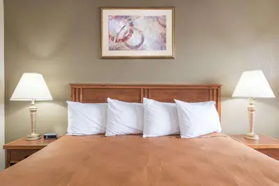 a bedroom with a bed with white pillows and two lamps at Red Carpet Inn Lancaster in Lancaster