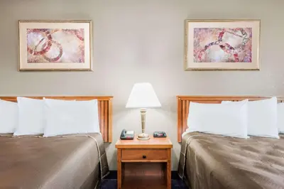 a hotel room with two beds and a table with a lamp at Red Carpet Inn Lancaster in Lancaster
