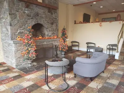 a room with a stone fireplace with two chairs and a christmas tree at Chateau Resort & Conference Center in Tannersville