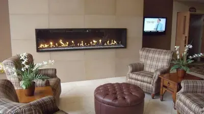 a living room with a fireplace and two chairs at Chateau Resort & Conference Center in Tannersville