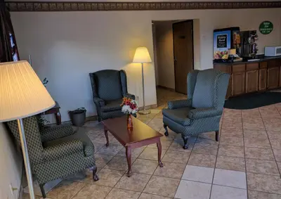a living room with chairs and a table and a lamp at Value Inn Harrisburg-York in Valley Green