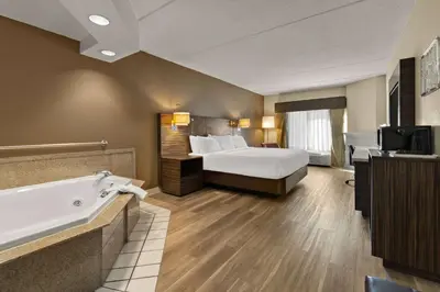 a hotel room with a bed and a bath tub at Ramada by Wyndham Harrisburg/Hershey Area in Harrisburg