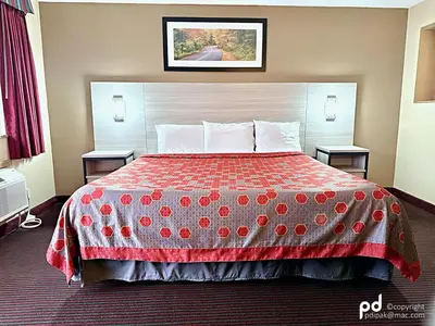 a hotel room with a bed with a red blanket at Travel Inn & Suites Flemington in Flemington