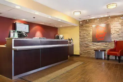 a restaurant with a bar and a red chair at Red Roof Inn Harrisburg - Hershey in Harrisburg