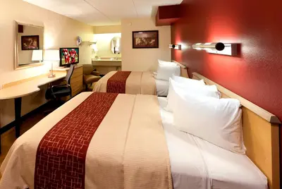 a hotel room with two beds and a desk at Red Roof Inn Harrisburg - Hershey in Harrisburg