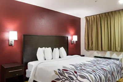 a hotel room with a large bed with red walls at Red Roof Inn York Downtown in York