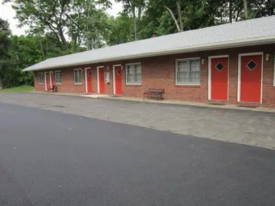 a red brick building with red doors and a bench at Cadet Motel in Cornwall-on-Hudson