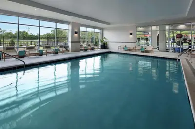 a swimming pool in a hotel with chairs and windows at Hampton Inn & Suites Teaneck/Glenpointe in Teaneck