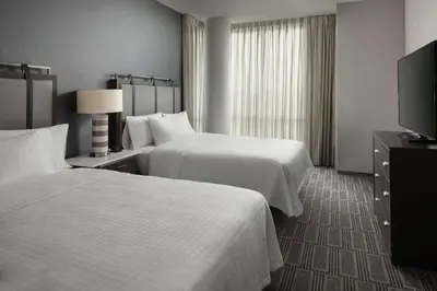 a hotel room with two beds and a flat screen tv at Homewood Suites By Hilton Teaneck Glenpointe in Teaneck