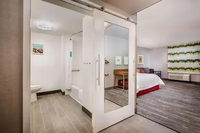 a bedroom with a mirror and a bed and a bathroom at Hampton Inn By Hilton Paramus in Paramus