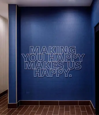 a blue wall with the words making you happy makes us happy at Hampton Inn By Hilton Paramus in Paramus